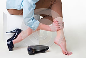 Cropped image of woman in high heels massaging her tired legs