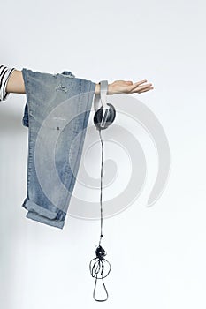 Cropped Image Of Woman Holding Jeans And Headphones Over White Background