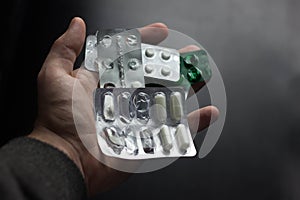 Cropped image of woman holding pile of blister packs with pills in hands