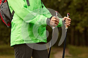 Cropped image of woman in light sports jacket holding Scandinavian sticks, getting ready to Nordic walking. Healthy