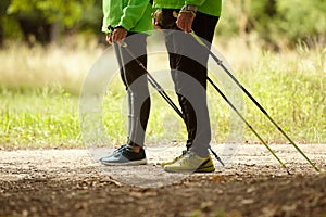 Cropped image of woman and man walking with Scandinavian sticks in autumn forest, outdoors. Nordic walking, healthy