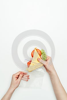 cropped image of woman packing sandwich in plastic ziplock bag on white