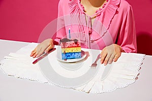 Cropped image of woman in pink shirt sitting at table with plate and birthday cake made of dishwashing sponges and