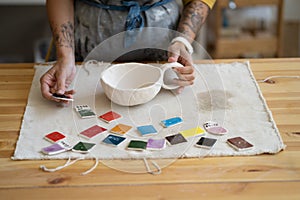 Ceramic painting. Woman ceramist choosing paint color, production process of handicrafter pottery photo
