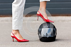 cropped image of woman in red high heels putting leg on motorcycle helmet on street