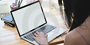 Cropped image woman is using a white blank screen computer laptop at the wooden working desk