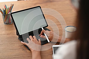 A cropped image of a woman is using a white blank screen tablet.