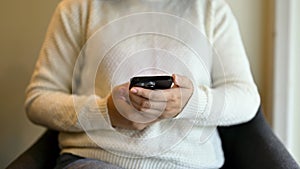 Cropped image of a woman using her phone while sitting at a chair in a coffee shop