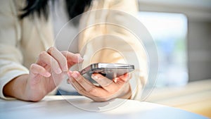 Cropped image of a young Asian woman using her smartphone, chatting, sending sms