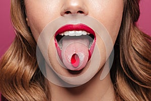 Cropped image of young lady with red lips holding pill in mouth