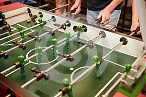 Cropped image of young people playing table soccer resting outdoors