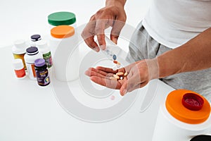 Cropped image of young sportsman holding vitamins and sport pills.