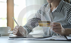 Cropped image of young woman holding credit card and using digital tablet