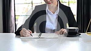 Cropped imaged of female lawyer writing important information on notebook, working at her office