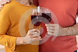 Cropped of loving couple holding glasses with red wine