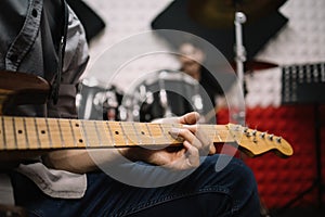 Cropped male musician playing guitar in studio