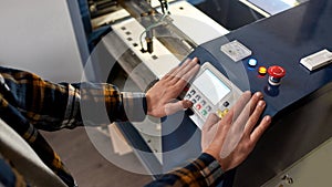 Cropped male worker pressing button on CNC machine