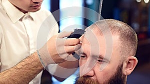 Cropped man hairdresser doing haircut. Cropped head of bearded man client on foreground. Finishing touches with trimmer