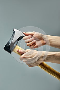 Cropped Man working in carpentry workshop, checking sharpness of ax blade