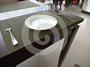 Cropped and partial view of dining arrangement with table and Empty plate and fork.