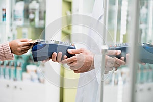 Cropped of pharmacist holding payment terminal