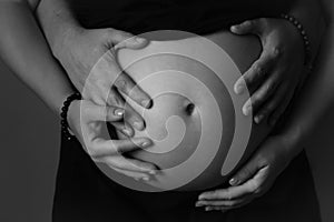 Cropped photo of beautiful pregnant woman and her husband hugging belly. pregnant woman poster