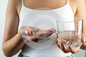 cropped photo of a beautiful young girl with a diet pill in one hand and a glass in the other.