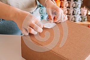 Cropped photo businesswoman hands packing, preparing parcel for delivery package to buyer. Silicone baby dish purshase