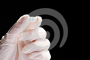 Cropped photo of a doctor hand in glove holding a remedy tablet with two fingers, concept of vaccination in the world.