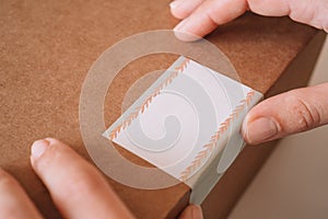 Cropped photo of female hands packing with scotch tape, parcel for delivery package to buyer. Woman sticks to box