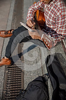 Cropped photo of guitarist holding notebook in the street