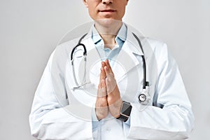 Cropped photo of male doctor or physician in white coat with stethoscope around his neck praying to God for help while