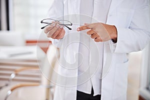 Optometrist in a lab coat showing prescription eyewear