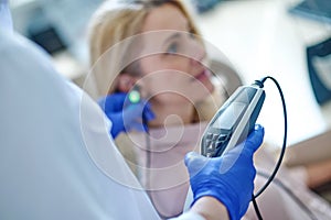 Experienced audiologist measuring the patients auditory acuity with an audiometer photo