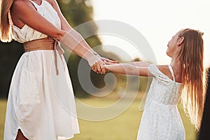 Cropped photo. Mother and daughter enjoying weekend together by walking outdoors in the field. Beautiful nature