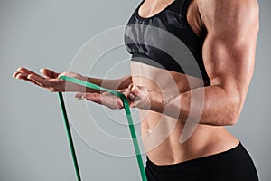 Cropped photo of musculary woman exercising with resistance band