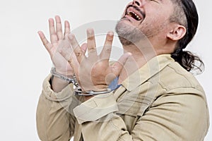 Cropped photo of a regretful man under arrest and in handcuffs cries and sobs in shame and remorse.  on a white background