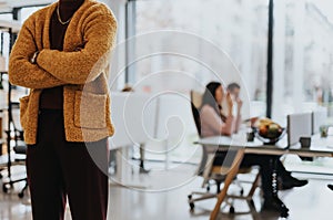 Cropped photo of stylish, unrecognizable, black businessman standing at modern office. People collaborating at the back