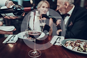 Cropped photo of Waiter pours wine in Restaurant