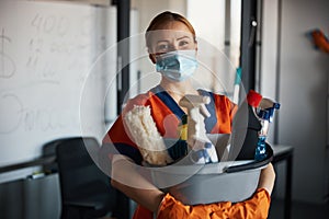 Cleaner in a face mask showing her cleaning products