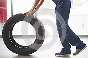 Cropped photo. Woman walks with brand new wheel to the car. Conception of repair