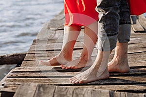 Cropped photo young lovers married couple, husband and wife, held of hands on a wooden bridge near lake. Rear view of