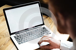 Cropped photo of young man using laptop on wooden table