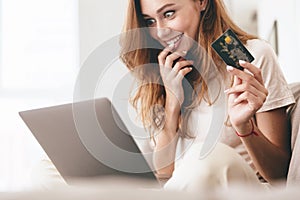Cropped picture of lady using laptop computer holding credit card.