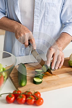Cropped picture of mature attractive man cooking salad.