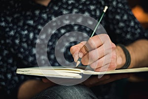Man writing in journal with a pencil photo