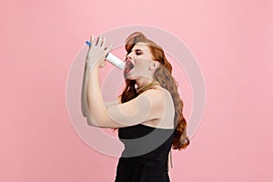 Cropped portrait of Caucasian woman singing in a tool isolated over pink background