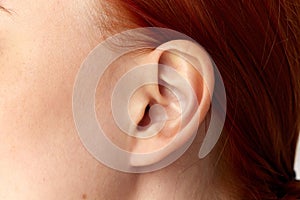 Cropped portrait with ear of young girl, woman, girl with red hair over white background. Close up image. Plastic