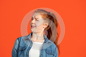 Cropped portrait of one young caucasian woman looking mistrustful isolated over red background