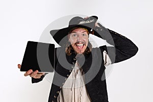 Cropped portrait of smiling man, medeival pirate in vintage costume pointing at tablet screen  over white